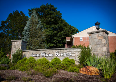 Jeanne Marie Gardens entrance with landscaping and stone welcome sign