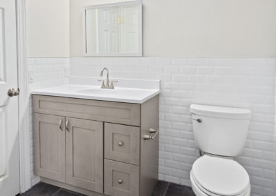 Bathroom on vinyl flooring with a toilet, vanity mirror and sink