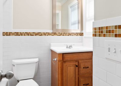 Bathroom with a wooden vanity, toilet, and subway tile on the walls