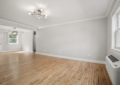 Living room with two chandeliers over the living and dining room space on hardwood-style flooring