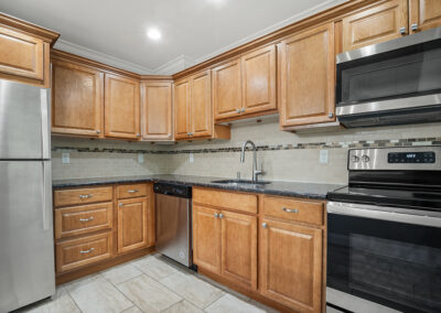 Kitchen with wooden cabinets, stainless steel appliances on vinyl flooring