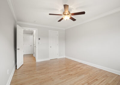 Bedroom with white walls, ceiling fan with lighting on hardwood-style flooring