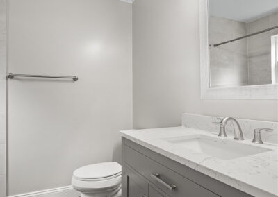 Bathroom with white walls, large sink, vanity on vinyl flooring.