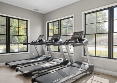 Treadmills next to large windows inside Jean Maria Gardens fitness center.